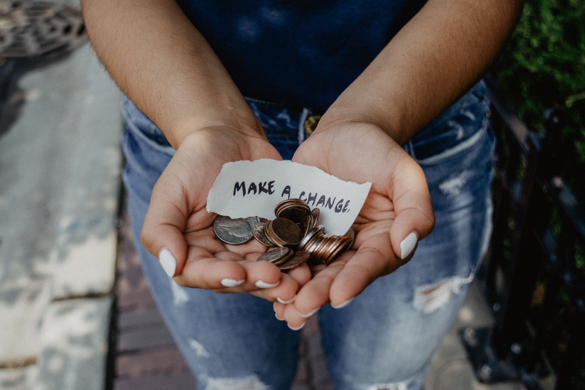 Image of hands holding a pile of a change and a note that says make a change. Photo by Kat Yukawa on Unsplash.